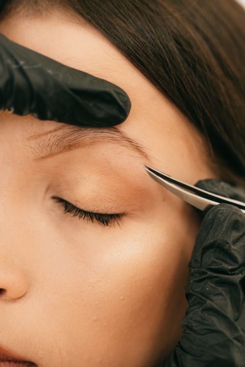 Eyebrow design with tweezers, close-up
